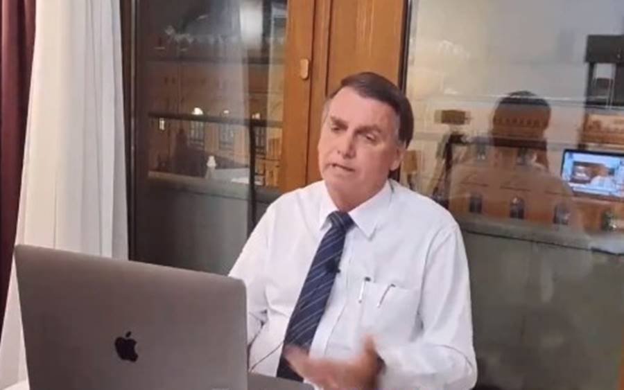 Bolsonaro dá entrevista para a Jovem Pan News. Ele está de frente para o computador com uma janela trás, vestindo camisa social e gravata - Metrópoles