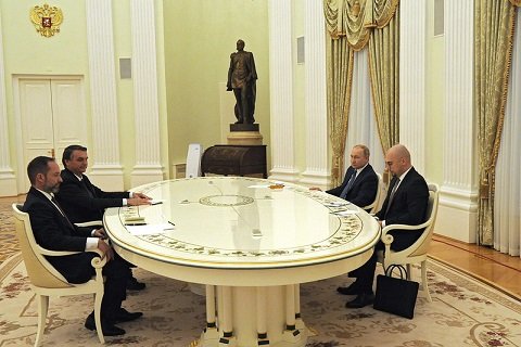 Bolsonaro e o presidente russo, Putin, conversam em lados opostos de uma mesa, Acompanhados de assessores no Kremlin.  Todos são homens brancos, e o salão é claro e amplo - Metrópoles