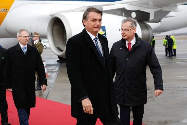 O presidente Bolsonaro (PL) desembarca de avião em aeroporto de Budapeste, na Hungria. Ele é branco, cabelo castanho e usa roupa de frio - Metrópoles