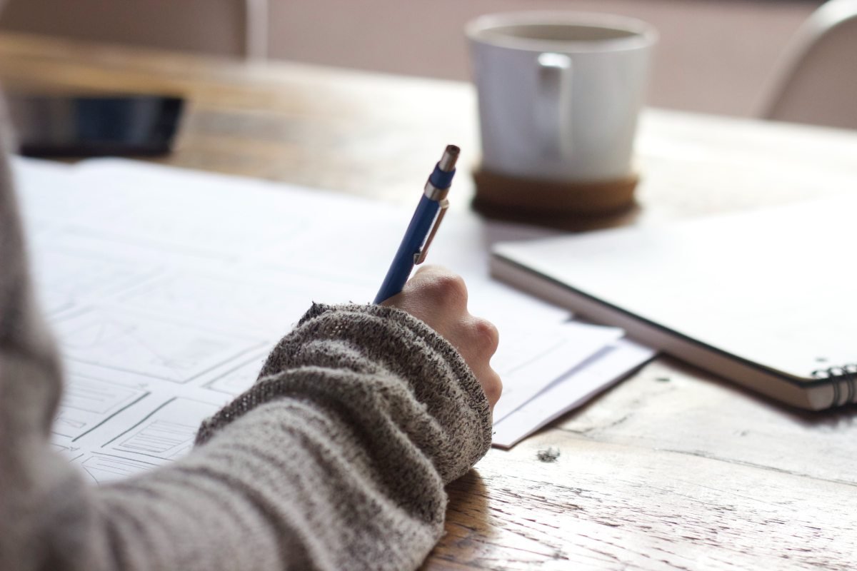 Braço de uma pessoa fazendo anotações em um caderno