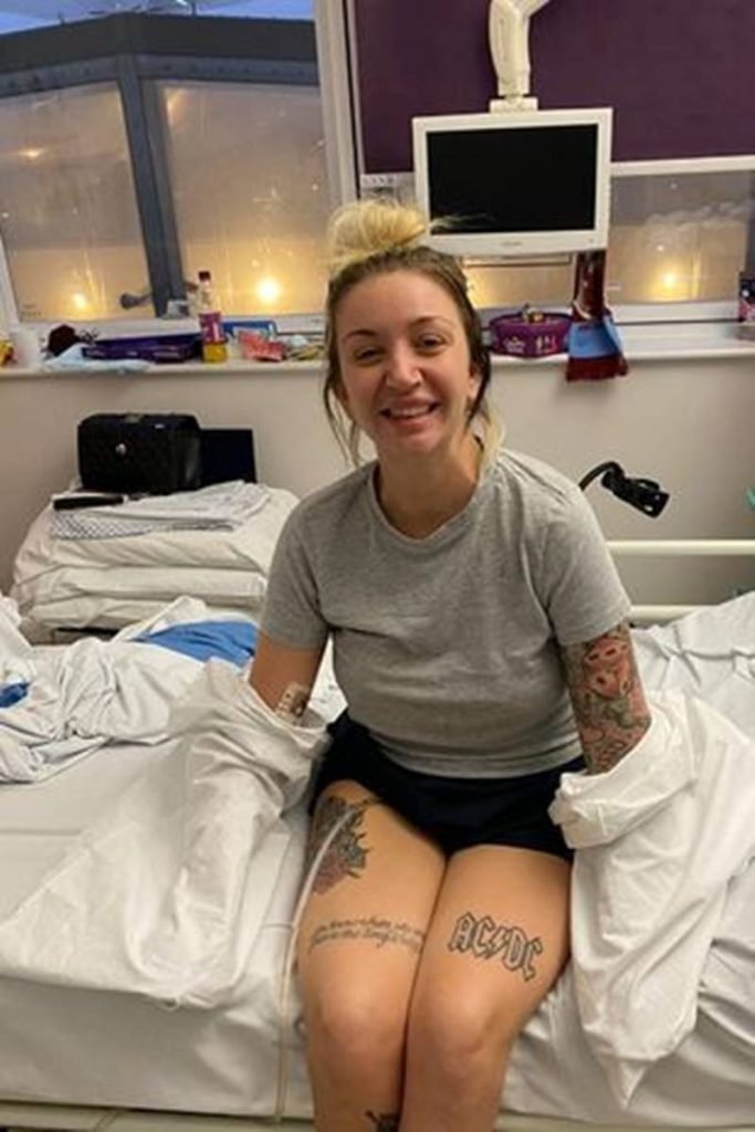Mulher sorrindo sentada em cama de hospital