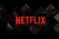 Logo da Netflix, na cor vermelha, em cima de um fundo preto com algumas capas de filme- Metrópoles