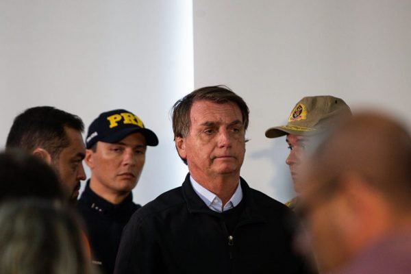 Bolsonaro ao lado de agentes da PRF e do governador do Rio de Janeiro, Marcelo Castro, em Petrópolis. Ele usa jaqueta preta - Metrópoles