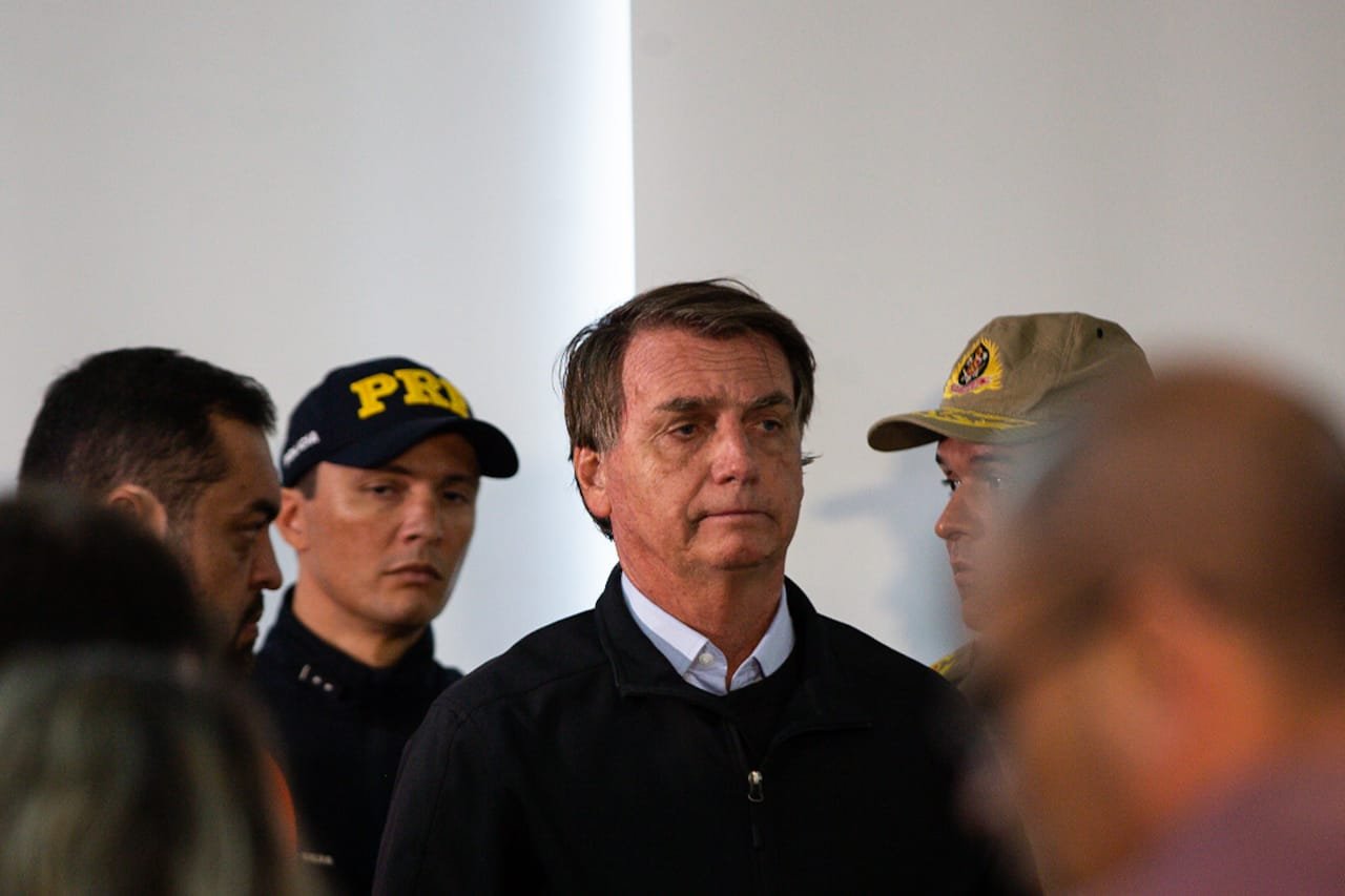 Bolsonaro ao lado de agentes da PRF e do governador do Rio de Janeiro, Marcelo Castro, em Petrópolis. Ele usa jaqueta preta - Metrópoles