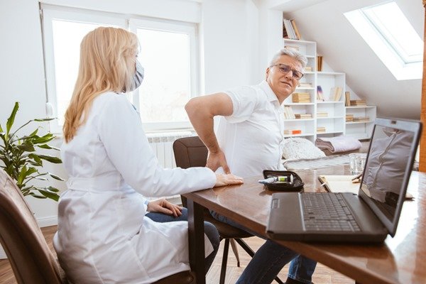 Pessoa aparentemente em uma consulta. O paciente está sentado enquanto uma mulher com jaleco o examina - Metrópoles