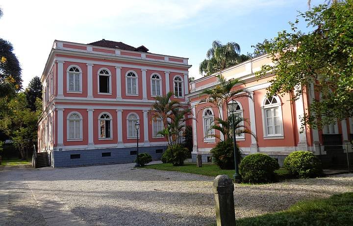 Vista da Companha Imobiliária de Petrólis, antiga casa da princesa Isabel. A casa é pintada de rosa e branco com várias janelas e um jardim
