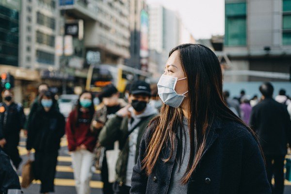 Mulher anda em rua movimentava usando máscara de proteção facila-Metrópoles