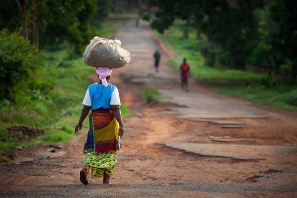 Mulher carrega sacola na cabeça enquanto anda em estrada de terra-Metrópoles