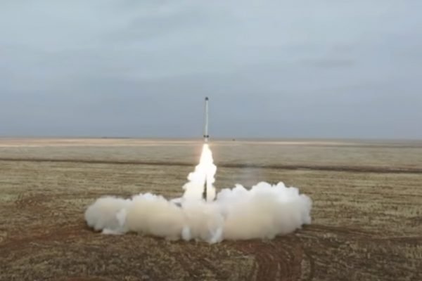 Mísseis lançados por Rússia em exercício militar. Num campo deserto, sob céu nublado, vê-se muita fumaça ao redor de um míssel em lançamento - Metrópoles