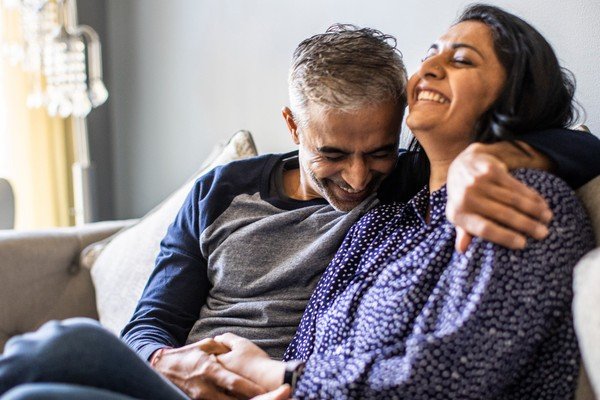 Smiling couple hugging on the sofa.  The woman has closed her eyes - Metropolis