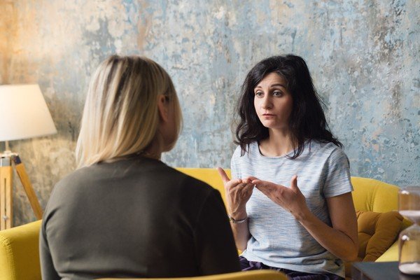 Mulher conversa com psicóloga em escritório. A especialista está de costas-Metrópoles