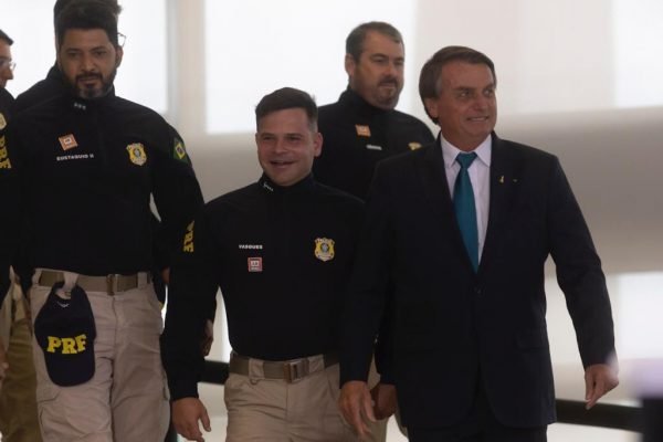 Em foto no Planalto, Bolsonaro desce a rampa com policiais rodoviários federais e sorri. Eles usam uniforme e o presidente terno. Nenhum usa máscara - Metrópoles
