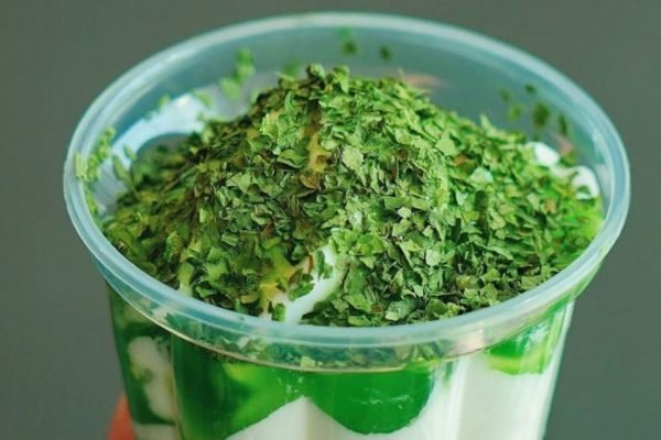 Na foto temos um copo de sundae com sorvete branco e calda verde