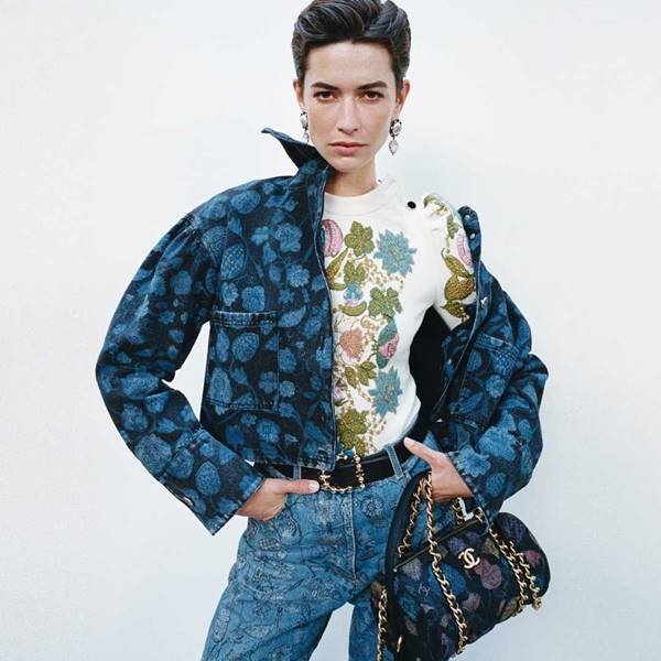 Modelo usa bolsa preta da Chanel com detalhes e corrente