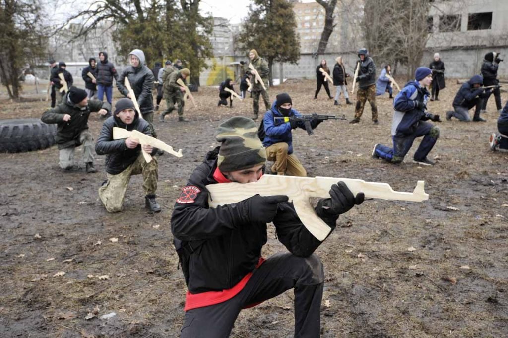 Ucranianos participam de treinamento militar para moradores, organizado por ativistas Kiev, Ucrânia. Os civis estão abaixados, num terreno de barro, como imitações de armas nas mãos - Metrópoles