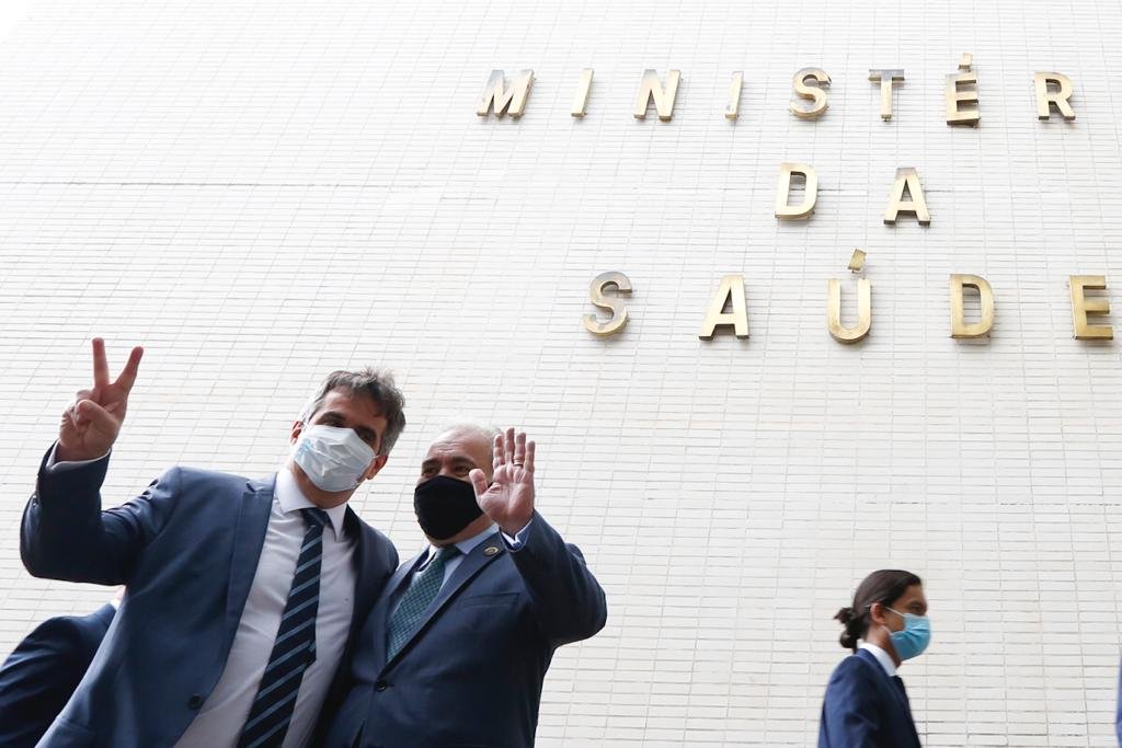 Na frente do Ministério da Saúde, Ciro Nogueira (PP-PI) e o ministro da pasta Marcelo Queiroga posam juntos para fotos e acenam. Ambos usam terno e máscara - Metrópoles