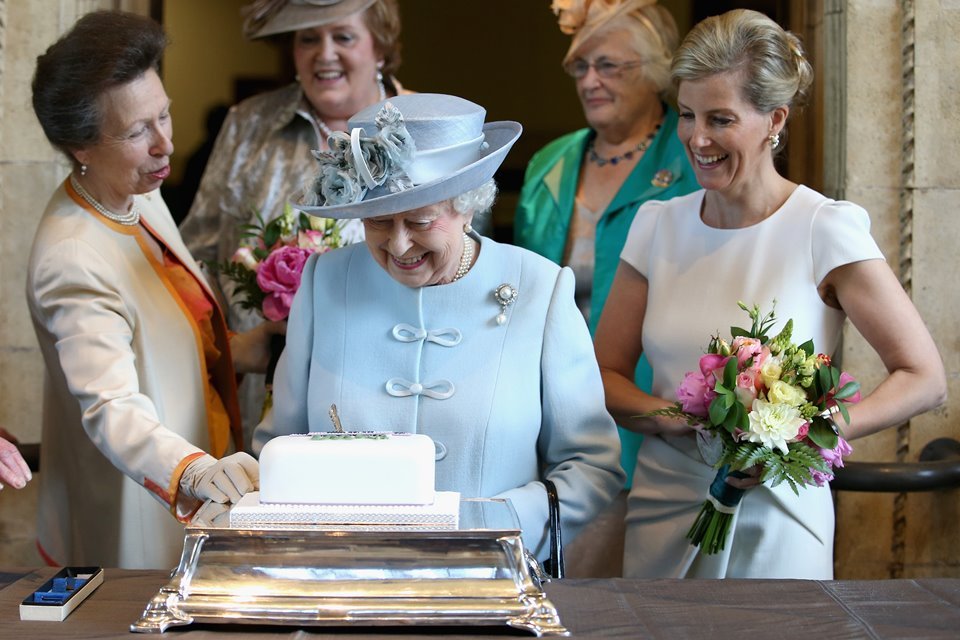 Mulheres estão ao redor de uma mesa com um bolo