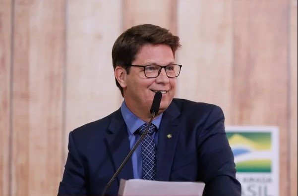 Mário Frias secretário de Cultura do governador Bolsonaro.  Ele usa terno escuro, camiseta azul, gravata azul e está em pé na frente de um microfone- Metrópoles