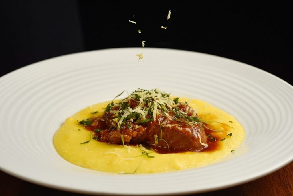 Na foto vemos um prato com polenta e linguiça