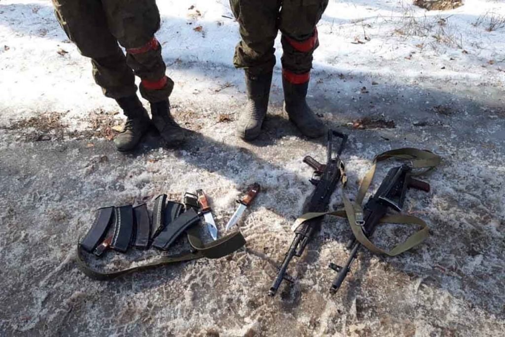 Foto mostra os pés e armas de dois soldados russos levados prisioneiro perto de Kiev, pela Ucrânia após a operação militar da Rússia na Ucrânia. Espalhadas no chão estão armas brancas, cartuchos e fuzis AEK-971 - Met
