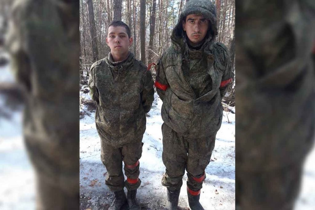 Dois soldados russos levados prisioneiro perto de Kiev, pela Ucrânia após a operação militar da Rússia na Ucrânia. Eles usam uniforme militar, tem o rosto ferido e estão com as mãos presas para trás em meio a uma floresta de gelo - Metrópoles