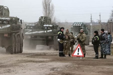 Tanques ucranianos são vistos em cidade da região após o ataque russo. Na foto, militares observam veículos militares seguirem por caminho de terra -Metrópoles