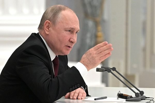 O presidente russo, Vladimir Putin, convoca reunião do Conselho de Segurança da Rússia no Kremlin. Ele está de lado falando ao microfone - Metrópoles
