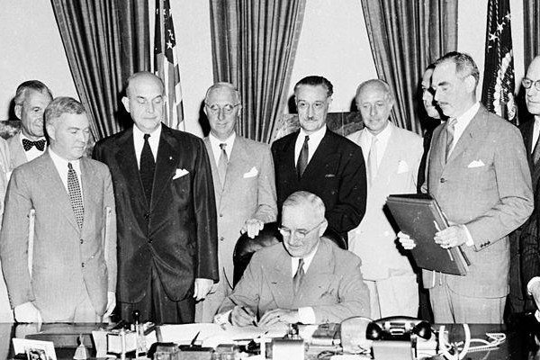 Imagem em preto e branco.  O presidente dos EUA, Harry Truman (sentado), na cerimônia de assinatura da criação da Otan em 1949-Metrópoles