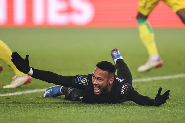 Neymar Junior, Brazilian soccer player.  He has dark hair, wears a football team uniform and is lying on the floor with his hands up.