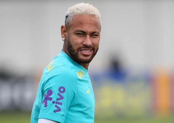 Neymar Júnior, futebolista brasileiro.  Ele tem cabelo oxigenado, veste uniforme de time de futebol e sorri ao olhar para frente: Metrópolis