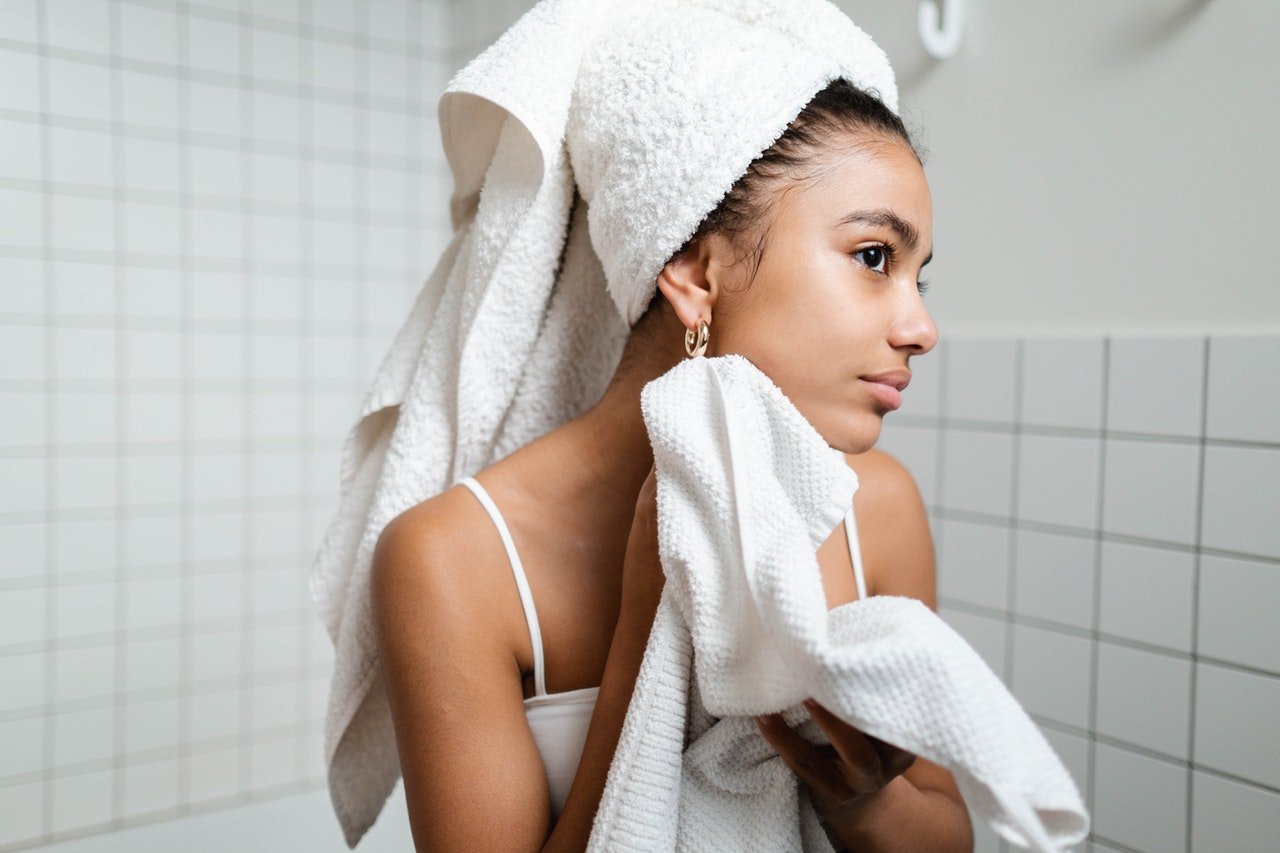 mulher jovem limpando o rosto com uma toalha