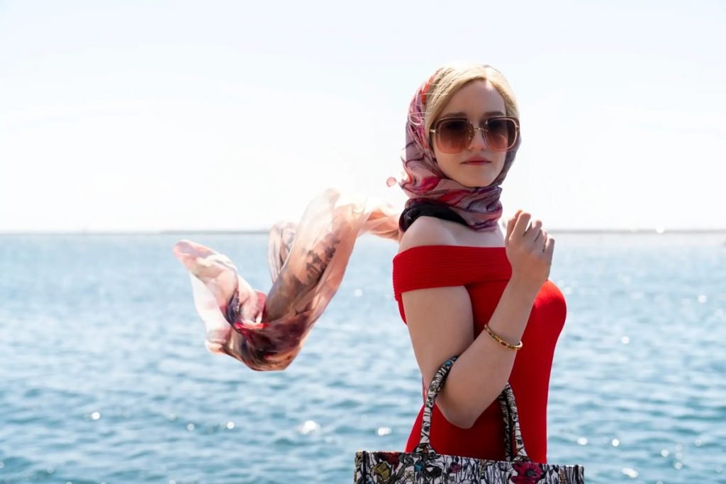 Eine Frau mit Schal, Brille und Tasche vor dem Meer