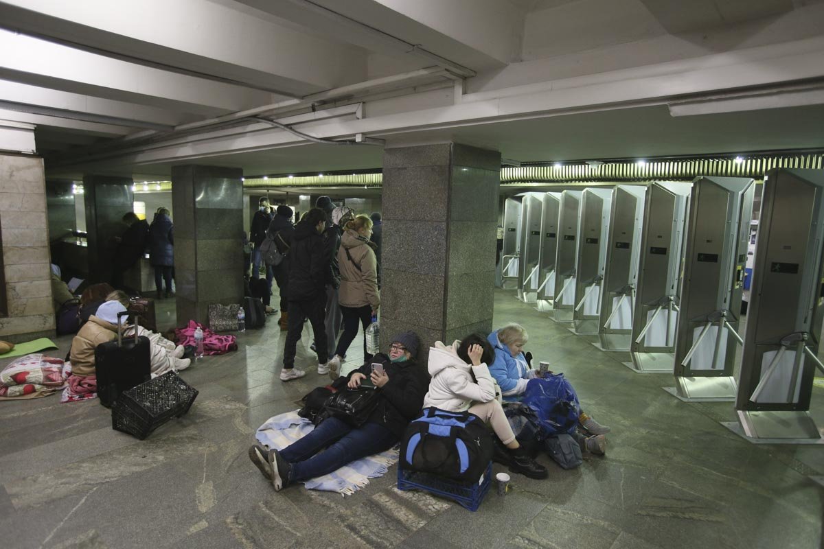 Pessoas se abrigam em estações de metro em Kiev, Ucrânia. Vários estão sentados no chão e alguns em pé - Metrópoles