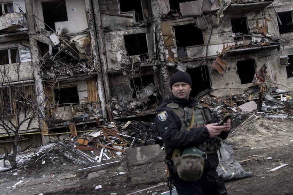 Policial ucraniano fica em frente a um bloco residencial atingido por um ataque de mísseis pela manhã em Kiev, Ucrânia