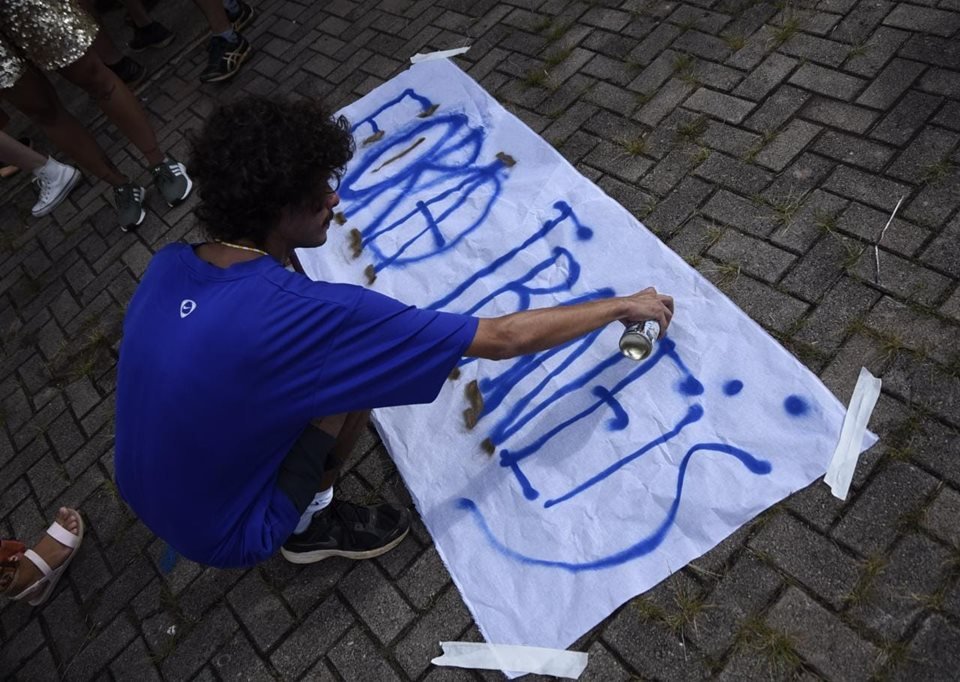 Menino de azul escrevendo em cartaz no chão