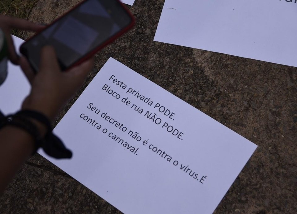 Mão segurando celular tirando foto de cartaz no chão