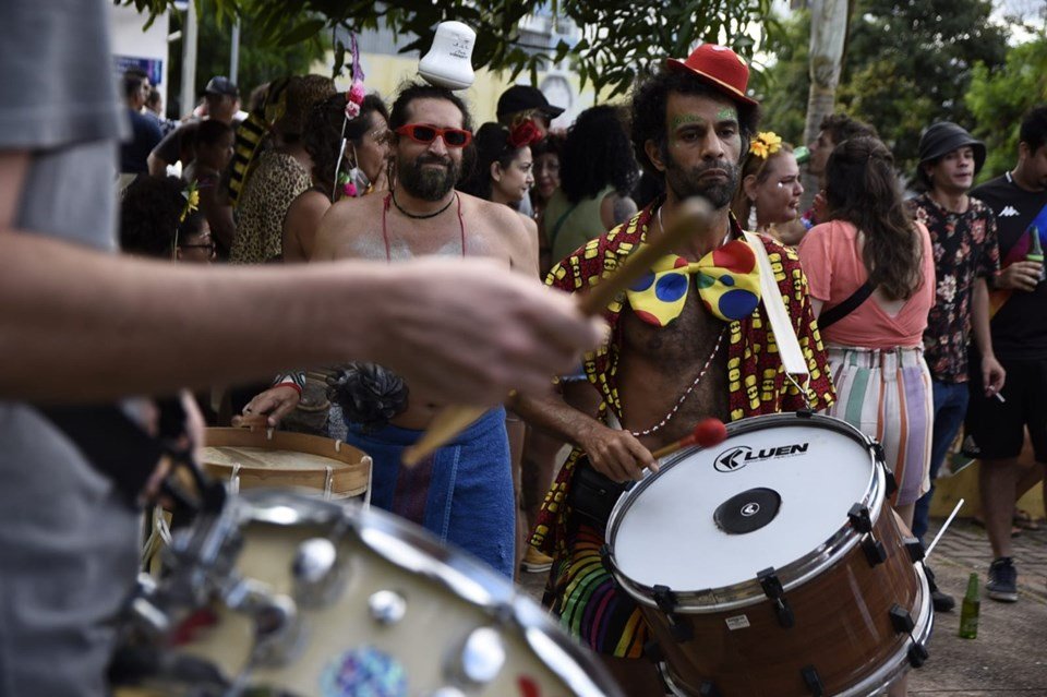 Pessoas fantasiadas tocando tambores e caminhando