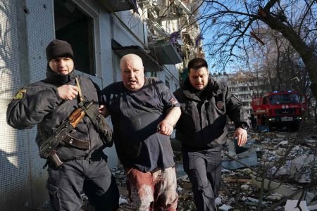 Forças de segurança ucranianas acompanham um homem ferido após um ataque aéreo atingir um complexo de apartamentos em Chuhuiv, Kharkiv Oblast, Ucrânia em 24 de fevereiro de 2022