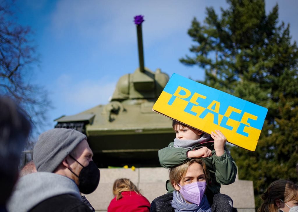 Participantes protestam contra a guerra na Ucrânia com uma placa com a inscrição 