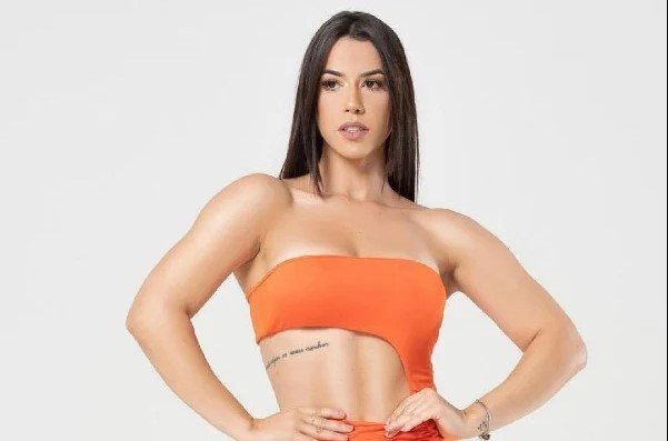 Larissa Tomásia, participante do Big Brother Brasil 22. Ela usa roupa laranjada e olha para o lado esquerdo - Metrópoles