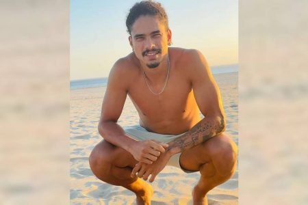 Homem agachado na praia