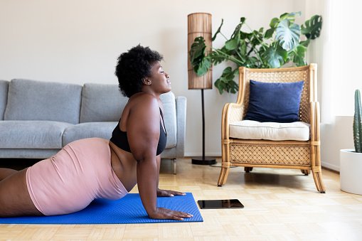 Mulher negra praticando yoga em casa