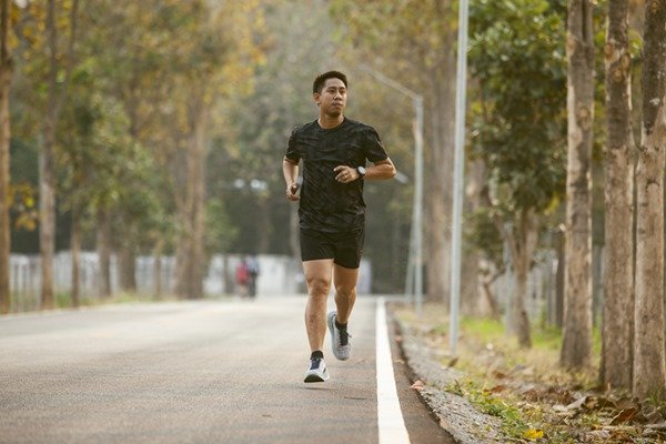 Man running on an empty street.  He wears black running gear - Metropolises