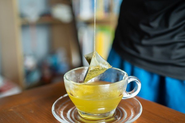 The image shows a transparent cup of tea in metropolis green