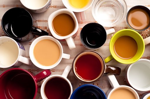 Várias xícaras de café com cores diferentes sendo fotografadas de cima