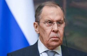 Ministro das Relações Exteriores da Rússia, Sergei Lavrov, fala de possível Terceira Guerra Mundial. Ele olha sério para frente com a bandeira russa atrás - Metrópoles