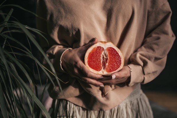 Mulher segura uma fruta vermelha perto do útero-Metrópoles