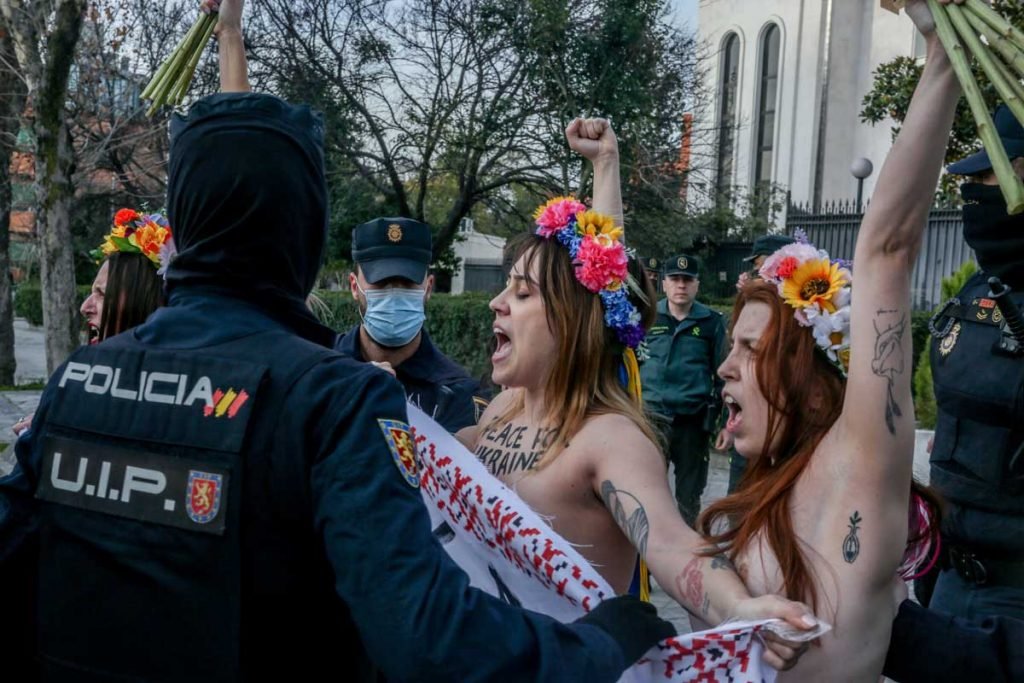 Duas mulheres levantam os braços enquanto vários agentes tentam expulsá-las de um protesto em frente à embaixada russa na Espanha, 3 de março de 2022, em Madri, Espanha