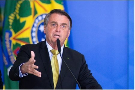 Bolsonaro discursa em coletiva com microfone. Ele veste terno preto e gravata amarela-Metrópoles