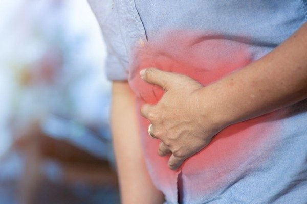 Man presses hand to stomach and appears to feel pain in area marked red - Metropolises